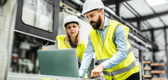 two workers on computer in manufacturing plant